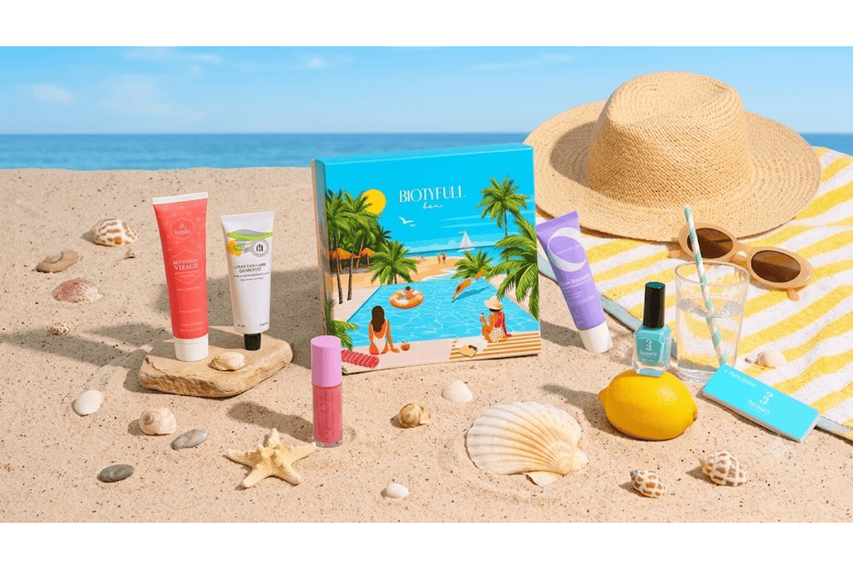 Biotyfull Box estivale sur sable avec chapeau de paille, lunettes de soleil, citron, et produits Bocia, Til, Baïja, Prim Aloé et 23Beauty disposés autour de la box