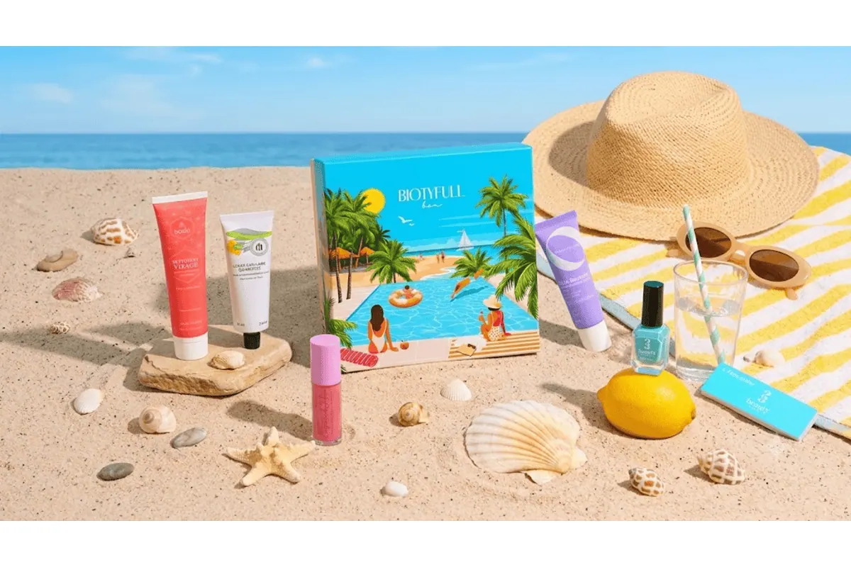 Biotyfull Box estivale sur sable avec chapeau de paille, lunettes de soleil, citron, et produits Bocia, Til, Baïja, Prim Aloé et 23Beauty disposés autour de la box
