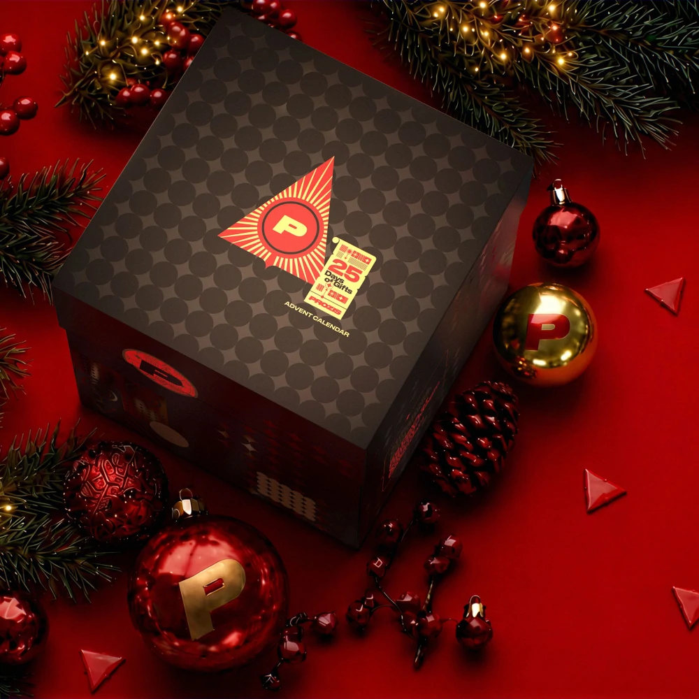 Vue du dessus du calendrier Prozis avec son couvercle à motifs et l’étiquette 25 jours, sur un décor de Noël rouge
