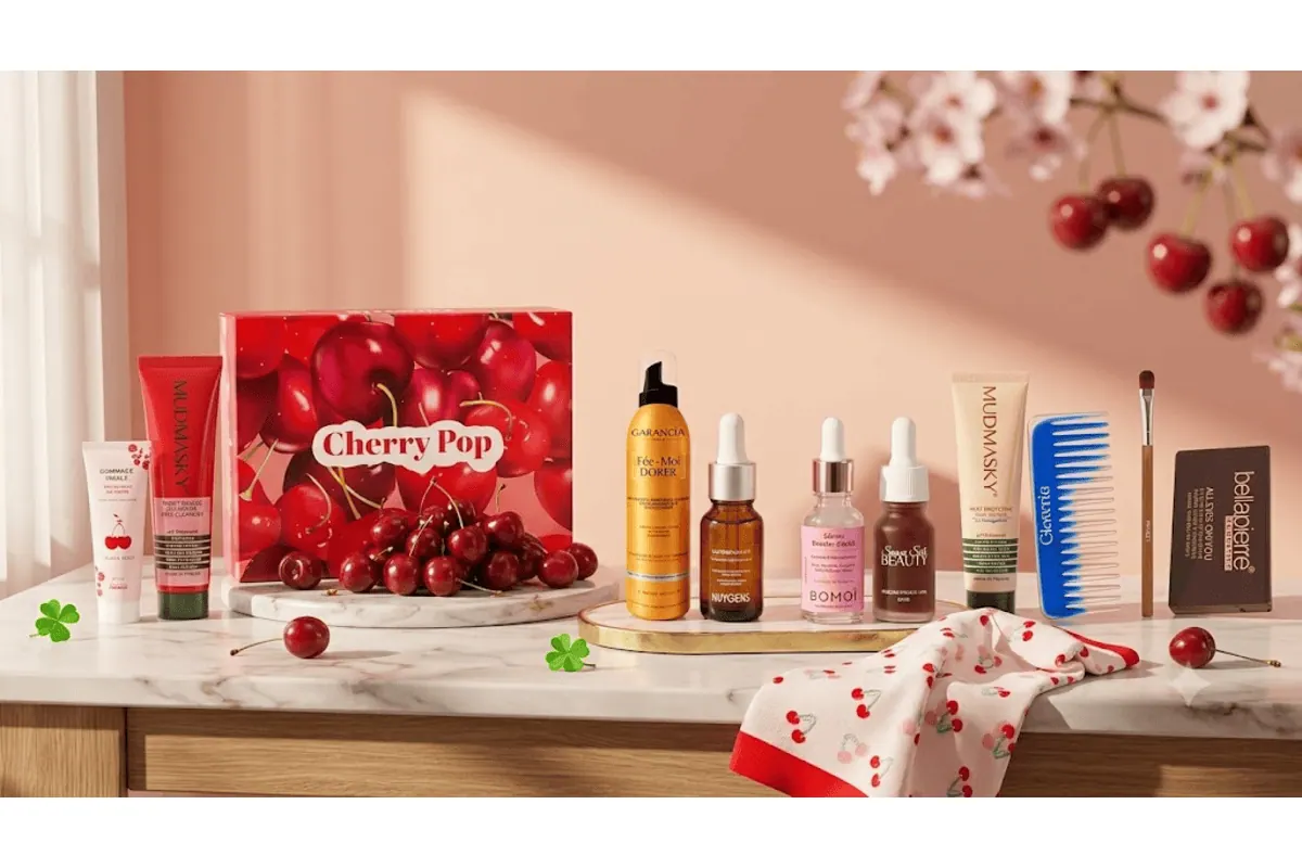 Box Glowria Cherry Pop estivale avec 13 produits beauté Mudmasky, Garancia, Huygens, Bomoï, Bellapierre, sur marbre rose avec branches de cerisier en fleurs