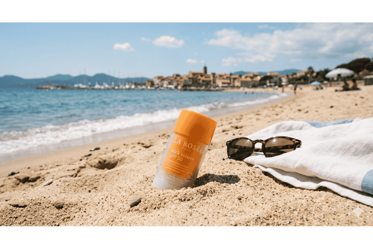 La Rosée stick solaire SPF 50 flacon orange plage sable lunettes écailles fouta rayée vue village Saint-Tropez