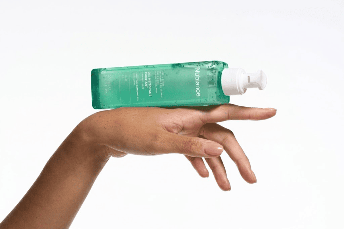 Flacon Nubiance Gel Nettoyant Purifiant vert transparent tenu dans une main sur fond blanc