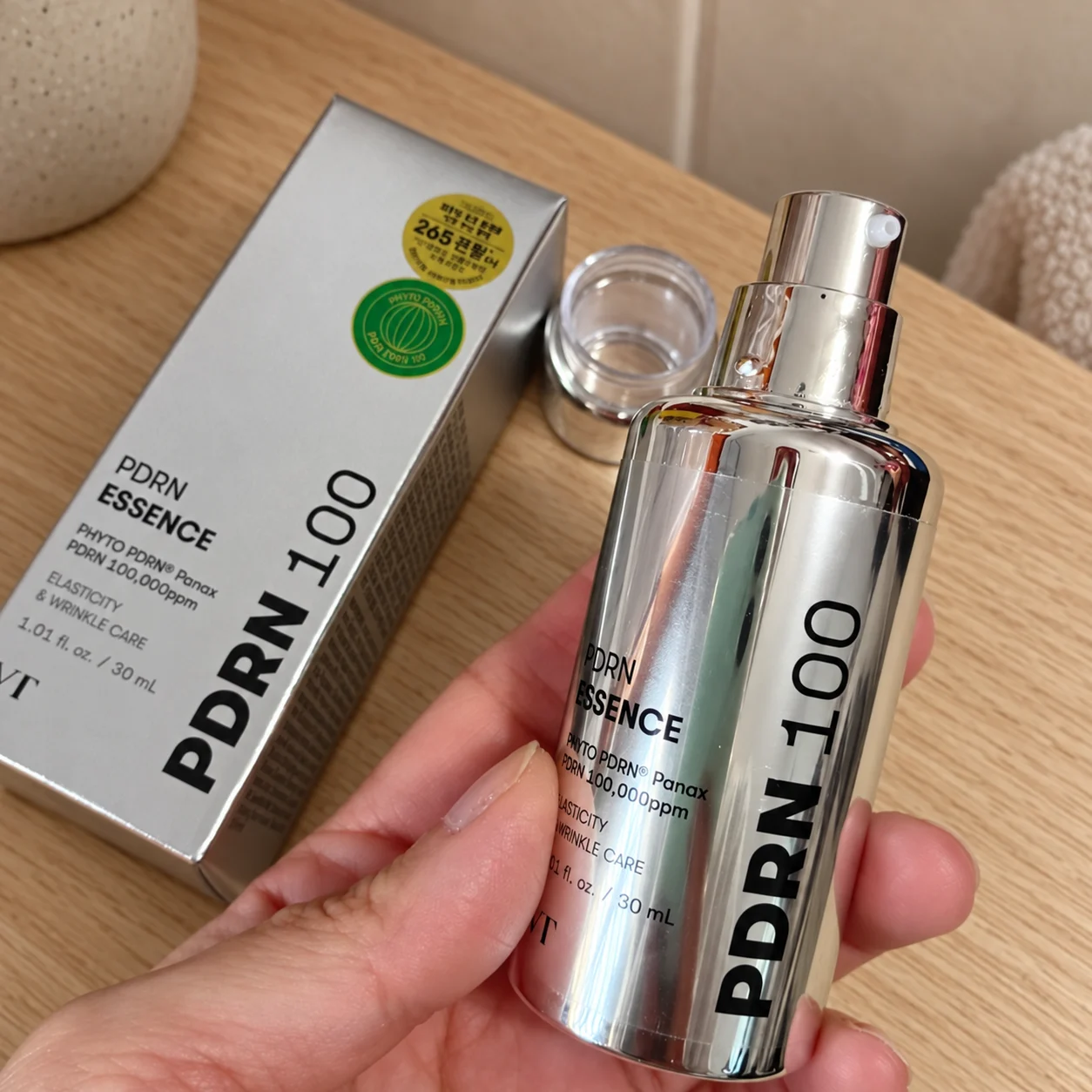 Pompe du flacon VT PDRN Essence 100 tenu en main avant la première utilisation